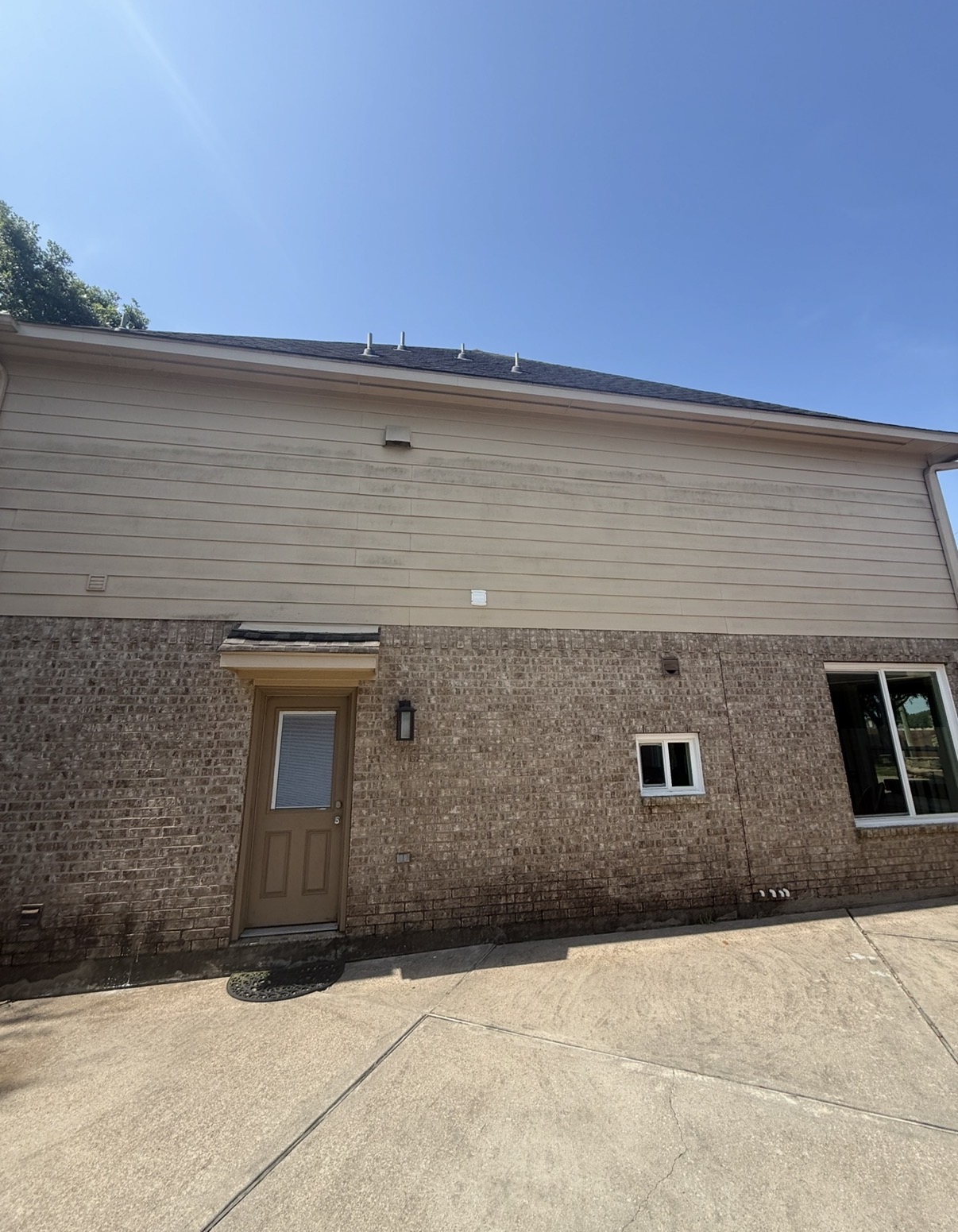 House siding and brick with algae staining before soft wash in Katy TX